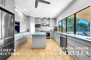 a kitchen with white cabinets and a blue counter top at Absolute Beachfront with Ocean Views 3 Beds plus Pool in Hideaway Bay