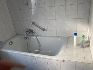 a bath tub with a shower head in a bathroom at Self check in ganzes Apartment 40 m zwei Schlafzimmer Wlan Parkplatz eigenes Badezimmer mit Badewanne Kochecke Einfamilienhaus in Duisburg