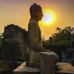 a statue of a woman sitting in front of the sunset at The Heritage Hotel in Polonnaruwa