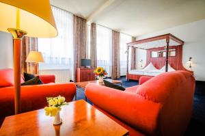 a living room with red furniture and a bed at Hotel Wilder Mann Annaberg-Buchholz in Annaberg-Buchholz