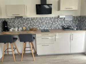 a kitchen with white cabinets and a counter with stools at Studio climatisé SPA en option in Jacou