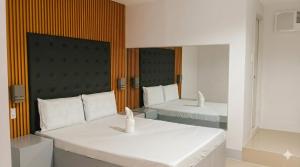 a hotel room with two beds and a mirror at D New Inn Mactan in Lapu Lapu City +10 photos