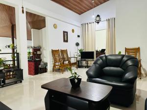 a living room with a black leather chair and a table at Kandyan Gate Homestay in Kandy