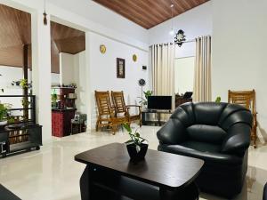 a living room with a black leather chair and a table at Kandyan Gate Homestay in Kandy +28 photos