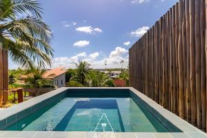 a swimming pool in front of a wooden fence at Aluá Patacho in Pôrto de Pedras