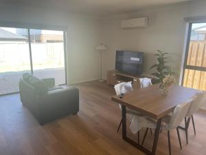 a living room with a table and a couch and a television at Southern Retreat in Clyde North