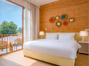 a bedroom with a large bed and a balcony at Thundi by Biosphere in Maalhos