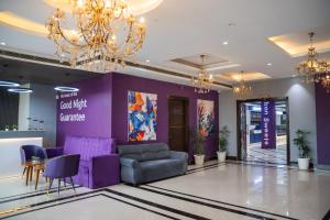 a lobby with purple furniture and a chandelier at Truva Hotel in Faridabad