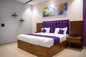 a bedroom with a large bed with a purple headboard at Truva Hotel in Faridabad +26 photos