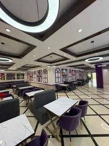 a dining room with tables and purple chairs at Truva Hotel in Faridabad