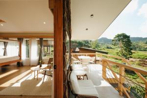 a room with a balcony with a bed and chairs at Campgrounds at Mantalongon in Dalaguete