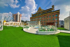a building with green grass and flowers in front of it at Nanyang King's Gate Hotel in Guangzhou