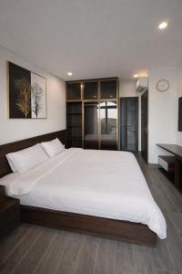 a bedroom with a large white bed and a desk at Tom Tom Homestay in Phú Quốc +3 photos