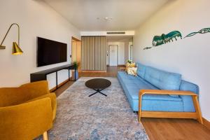 ein Wohnzimmer mit einer blauen Couch und einem Fernseher in der Unterkunft Crystalbrook Flynn in Cairns