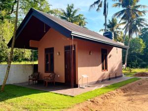 a small pink house with a porch and chairs at Villa Mistica - Hiriketiya Dikwella in Dickwella