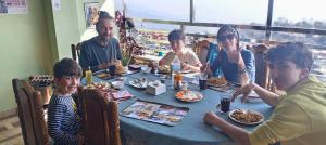 a group of people sitting around a table eating food at Sunshine homestay in Tānsen +161 photos