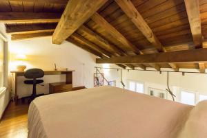 ミラノにあるAppartamento Cairoliの白いベッドと木製の天井が備わるベッドルーム1室が備わります。