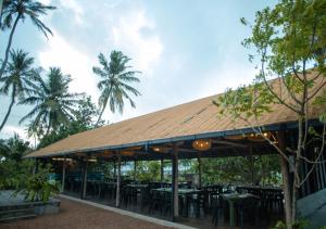 a restaurant with tables and chairs and palm trees at The Dutch Station Hotel in Ambalangoda