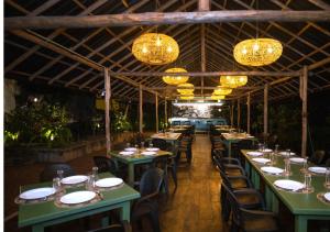 a restaurant with green tables and chairs and chandeliers at The Dutch Station Hotel in Ambalangoda
