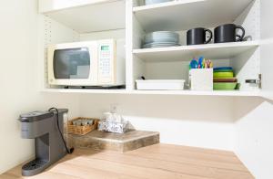 a kitchen with a microwave and a shelf with dishes at 3Beds Ground-Level Private Suite in Burnaby in Burnaby