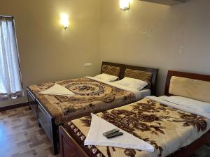 two beds in a small room with at Zioneliteresidency in Kodaikānāl
