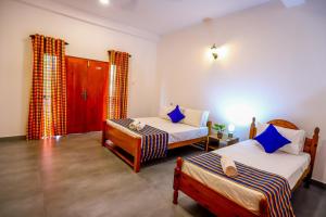 a bedroom with two beds and a door with a window at Negombo Lagoon Hideaway in Negombo