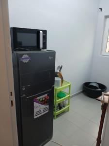 a black refrigerator with a microwave on top of it at Christal house in Abomey-Calavi