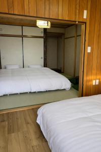 two beds in a room with wooden walls at KAMIKURA stay in Shingū