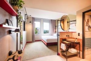 a bathroom with a bed and a sink and a mirror at Me and All Hotel Berlin East Side, by Hyatt in Berlin