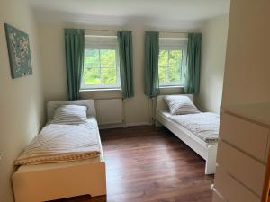 zwei Betten in einem Zimmer mit zwei Fenstern in der Unterkunft Friesenwald in Zetel