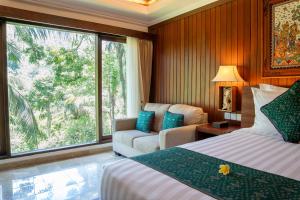 a hotel room with a bed and a couch and a window at Ayung Resort Ubud in Payangan