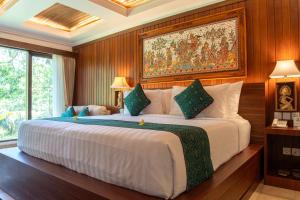 a bedroom with a large bed with a painting on the wall at Ayung Resort Ubud in Payangan