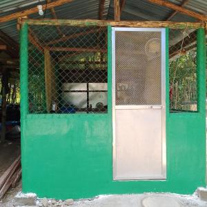 a green doorway with a white door and a fence at Nory's Tourist Inn in San Vicente