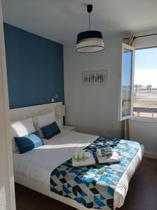 a bedroom with a bed with a blue wall at Hôtel de la Mer in Valras-Plage