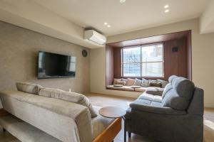 a living room with a couch and a tv at A&m花畑401 in Kumamoto
