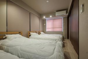 a room with three beds and a window at A&m花畑401 in Kumamoto