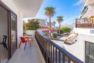 a balcony with a table and chairs and palm trees at El Nido Apartment in Acantilado de los Gigantes