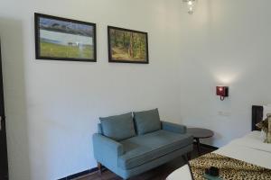 a living room with a blue chair and two pictures on the wall at Ranthambhore Aangan in Khilchipur