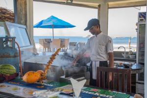 a man cooking food on a table in a kitchen at Hotel Lanka Super Corals in Hikkaduwa