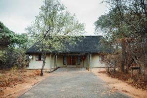 a small white house with a thatched roof at Awelani Eco Tourism Lodge in Masisi