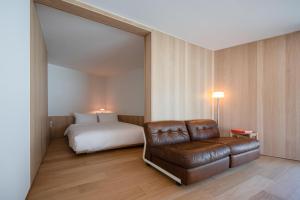 a room with a bed and a couch and a bed and a chair at 롯지호텔 디여라 in Andong