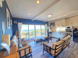 a living room with a couch and chairs and a kitchen at パーティーができるビーチハウス海まで1分一棟貸切Qiao105屋外犬可 in Hokota