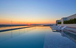 a pool with chairs and the sunset in the background at JI Hotel Vientiane Mekong Riverside in Vientiane