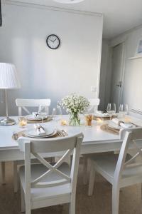 a white dining room table with chairs and a clock on the wall at Frost Longstay City in Kiruna +9 photos