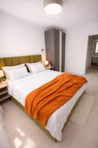 a bedroom with a large bed with an orange blanket at Olympus City Escape in Bucharest