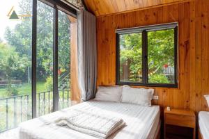 a bedroom with a bed and a large window at Trại Mít Farm in Sóc Sơn