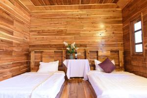 two beds in a wooden room with a table at Trại Mít Farm in Sóc Sơn