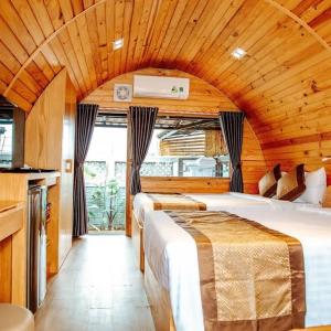 a bedroom with two beds in a room with wooden ceilings at Trại Mít Farm in Sóc Sơn