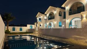a villa with a swimming pool at night at Larissa Resort in Nashik
