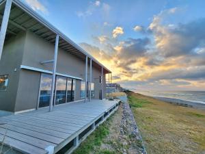 a building with a wooden deck next to the ocean at ゲストハウス＆カフェ　ハレテル in Masuda